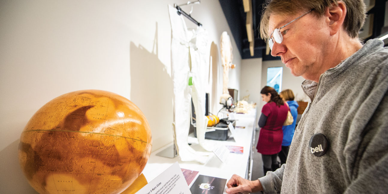 Man looks at a globe of Mars.
