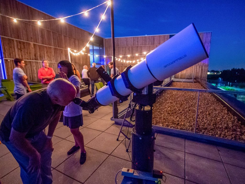 A man looks into a large telescope pointed toward the night sky