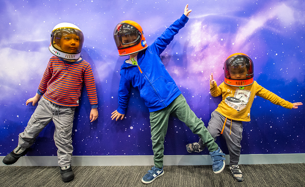 Kids in space helmets in front of the Bell's space wall