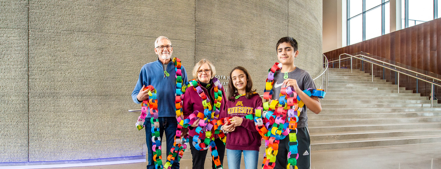 A family holds a paper chain with the digits of pi