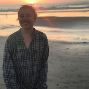 anna smiles on a beach at sunset