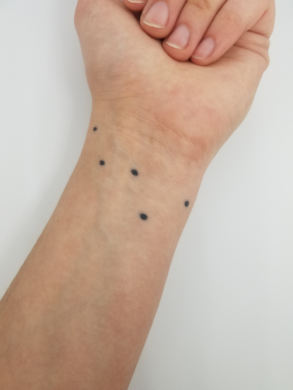 Tattoo on wrist (five black dots)