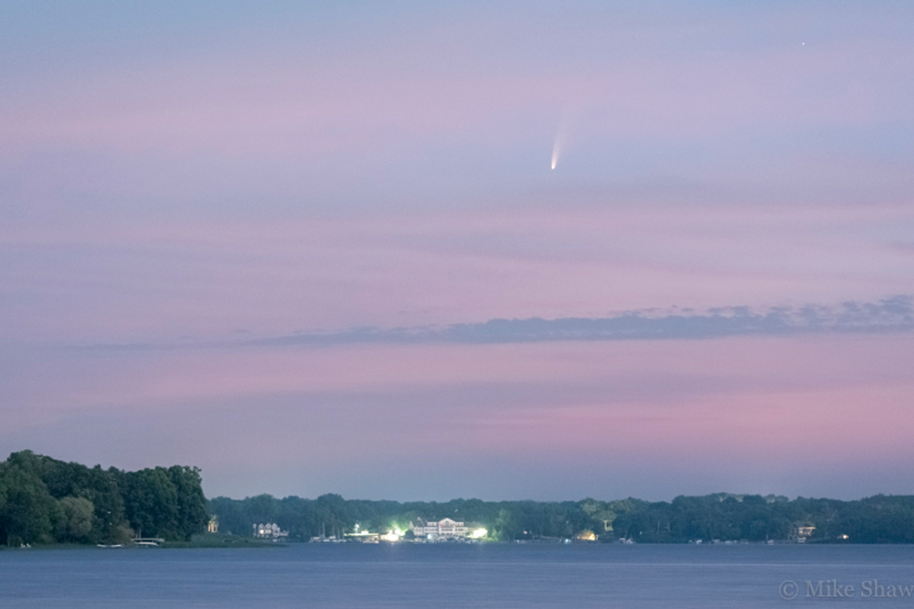 Pink and blue skies over lake with comet in the sky