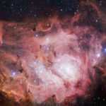 A complex and mesmerizing pink nebula with wisps of red among the stars
