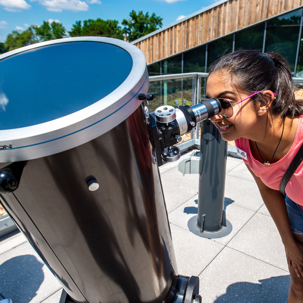 girl looking into large telescope