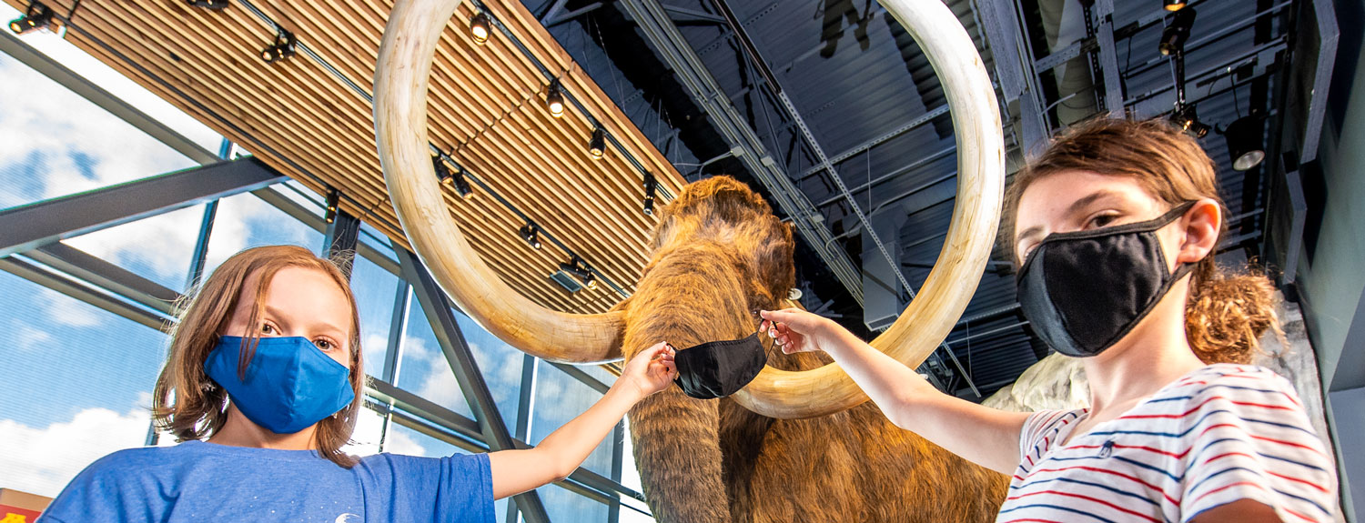 Kids holding face mask up to woolly mammoth