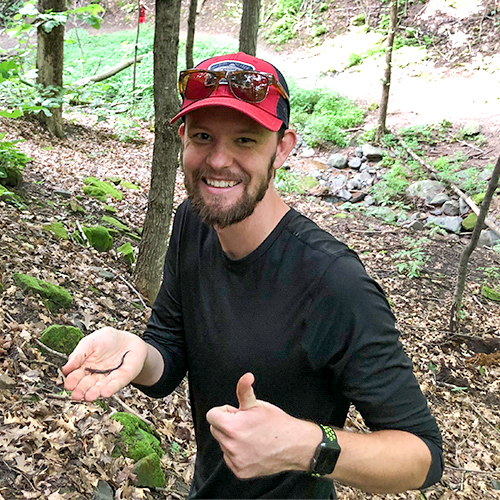 Person smiling holding salamander with thumbs up