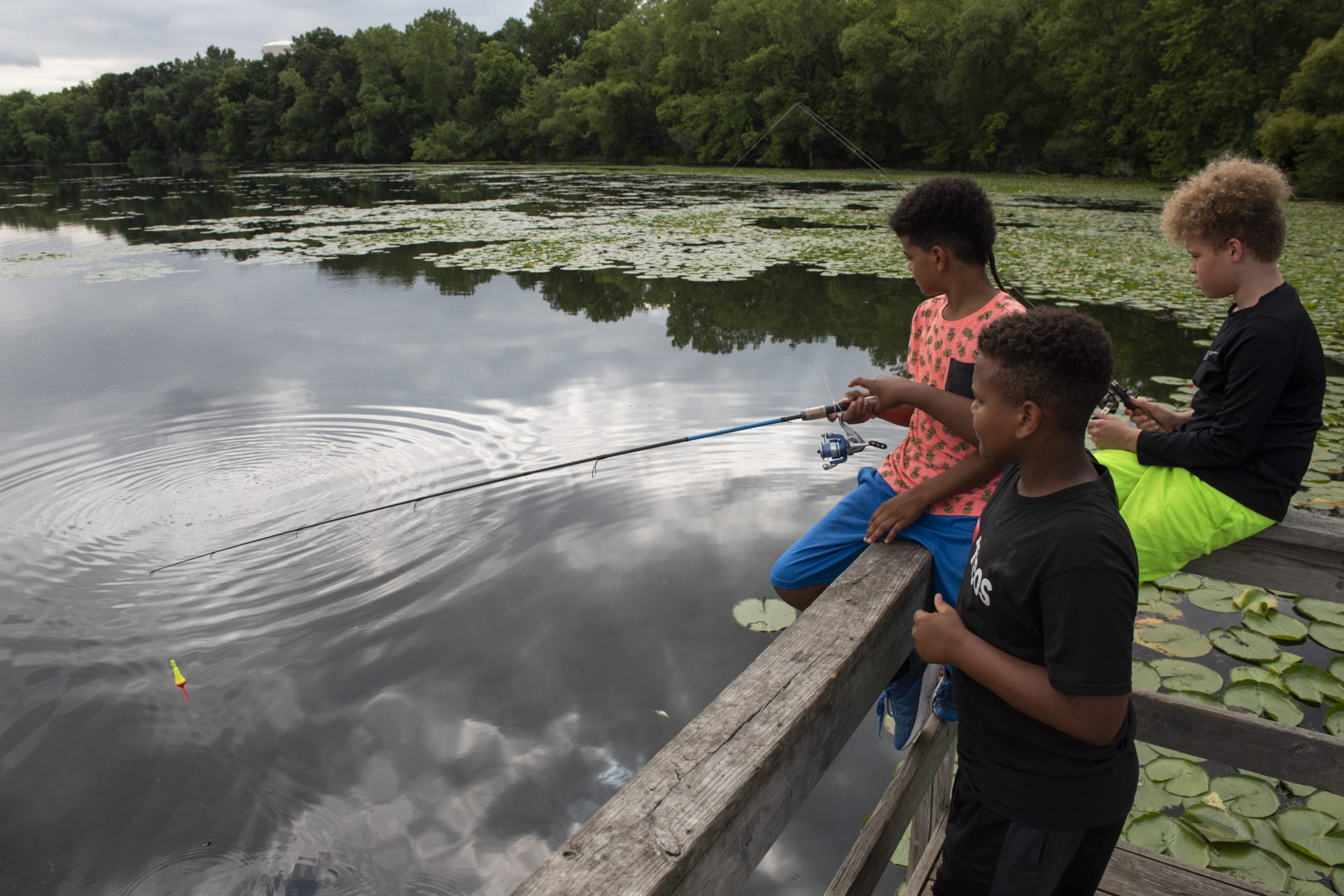 A group of three kids fishing off a dock