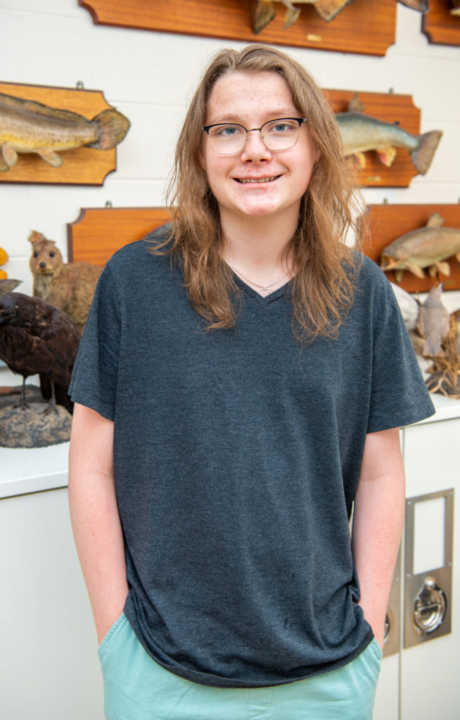 A high school intern standing in front of fish specimens