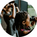 Children with binoculars looking out a window at birds