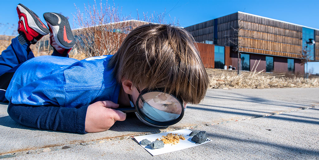 Young child looking at rocks with magnify glass
