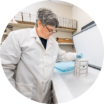 Curator Keith Barker in lab coat holding a DNA research specimens