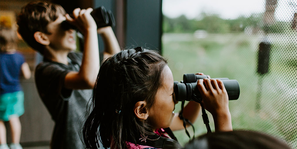 two children looking out the window through the binoculars