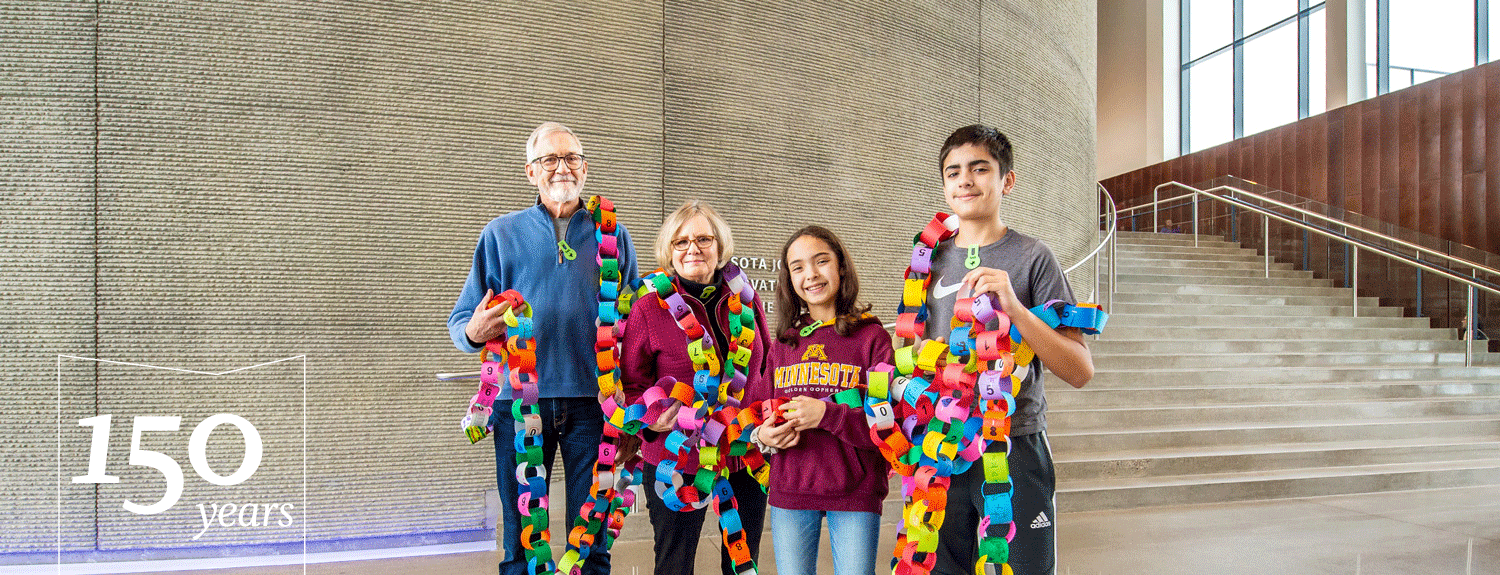 A family holds a paper chain with the digits of pi with text: 150 years