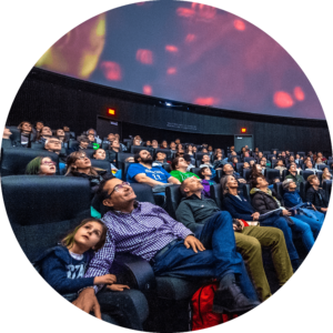 Group of people smiling and looking up at planetarium screen