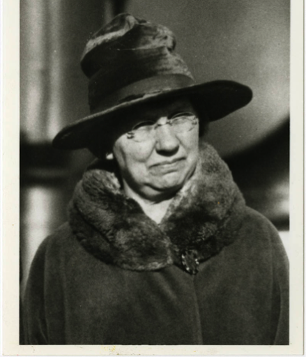 A sepia toned photograph of an elderly woman wearing a black hat