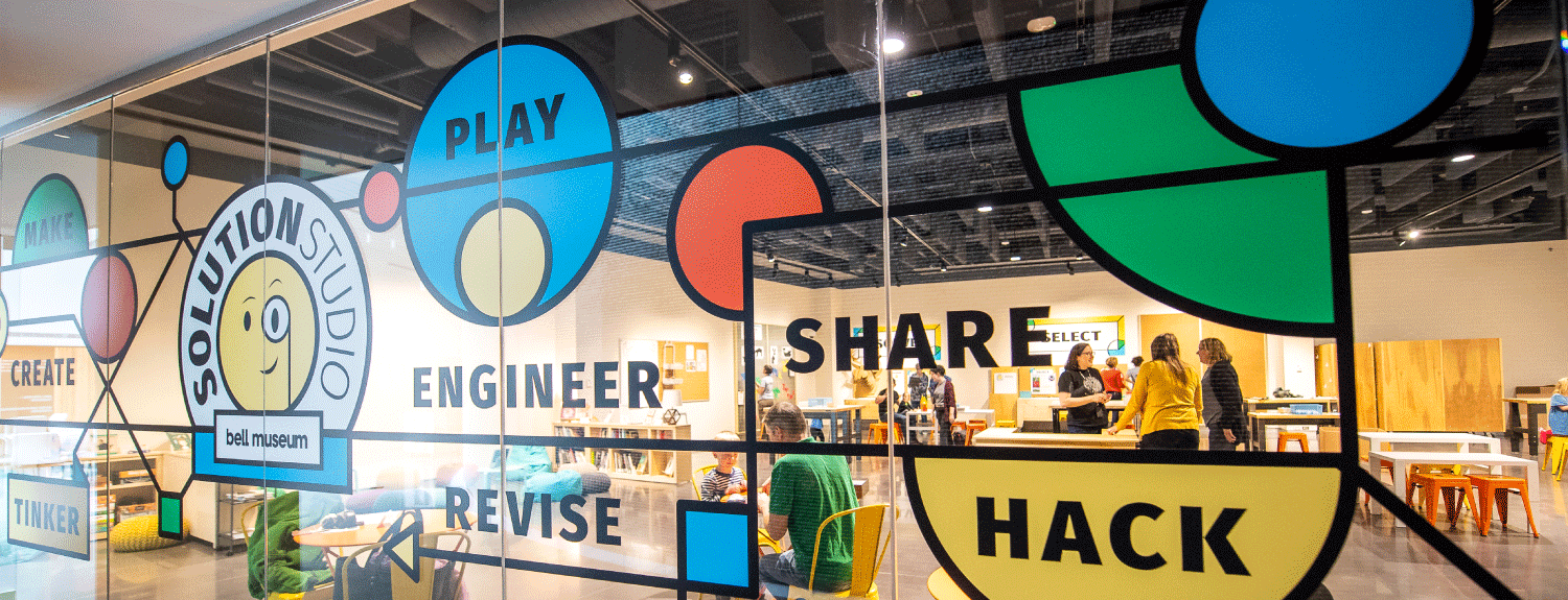 Glass with colorful decals with text that reads: make, create, tinker, play, engineer, revise, share, and hack.