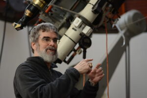 Br. Guy Consolmagno standing next to telescope. 