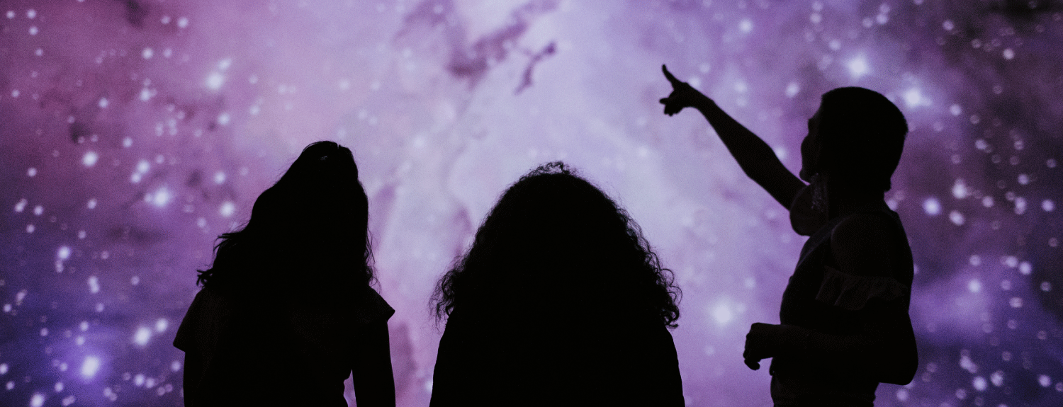 Silhouette of three people in planetarium.