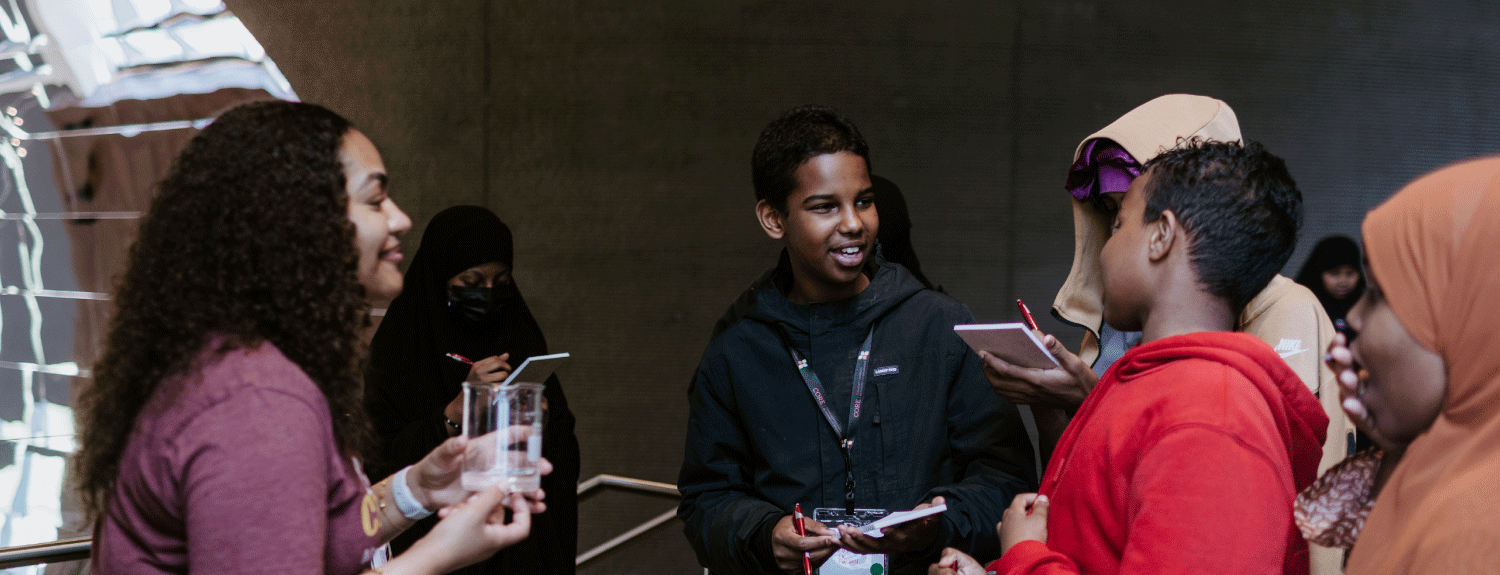Visitors interacting with a researcher holding a beaker.