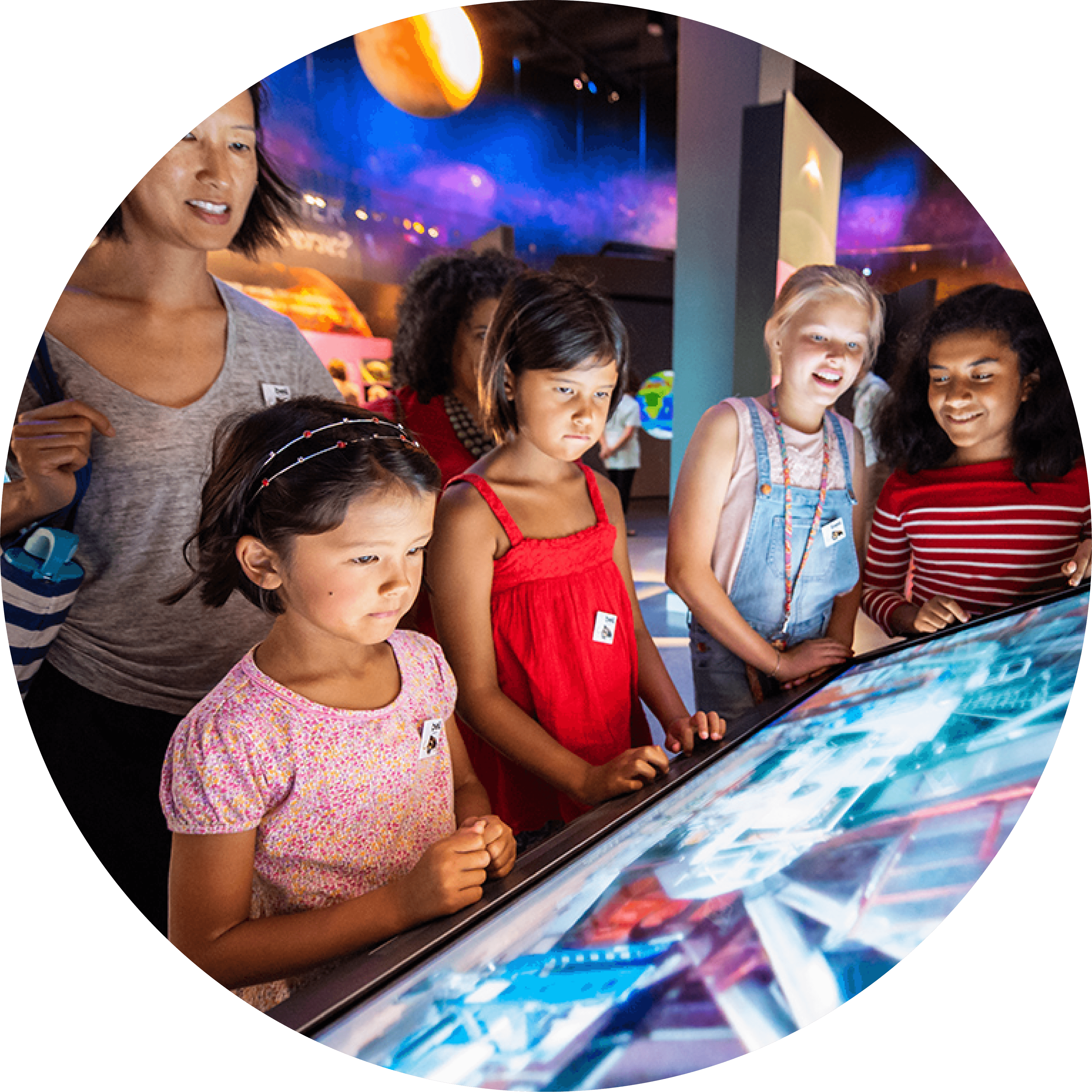 Adult with group of children looking at digital display at the museum.